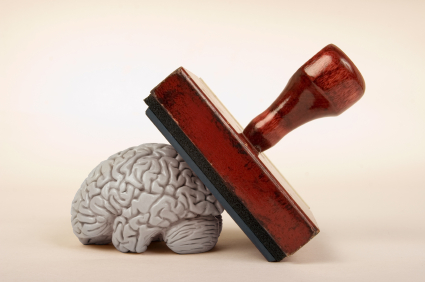 An image of a rubber stamp pressing down on a gray model of a human brain against a beige background. The concept suggests an intersection between approval, authority, or decision-making and the human mind, much like tools for local government managers shaping community decisions.