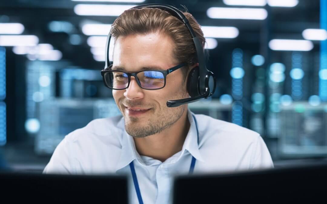 A staff with headphones talking to clients while facing his desktop