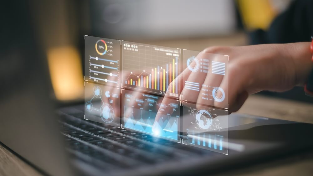 A person's hands are typing on a laptop keyboard, with holographic data visualizations and charts appearing to float above the screen. The charts display various metrics, including bar graphs, line graphs, and pie charts, indicating data analysis activities related to covid-19.