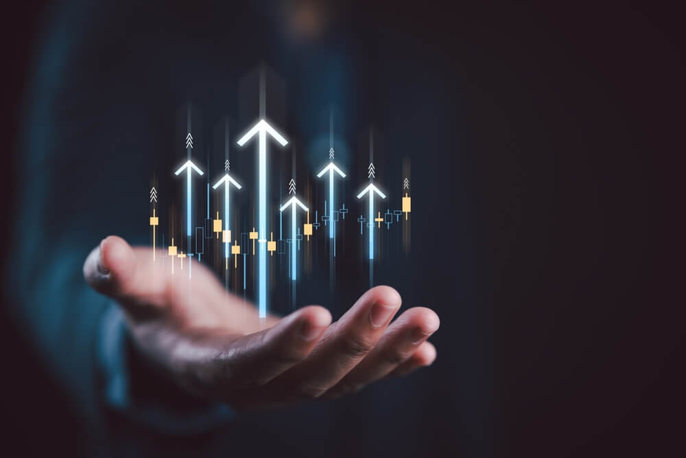 A person extends their hand, with glowing arrows and digital charts hovering above the palm. These upward-pointing arrows symbolize growth and progress, representing the essence of leadership. The dark background accentuates a futuristic theme of technology and advancement.